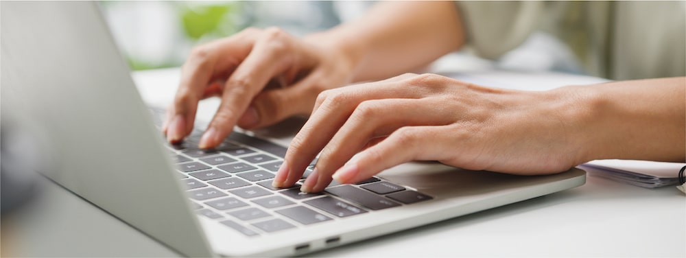 Hands typing on silver laptop